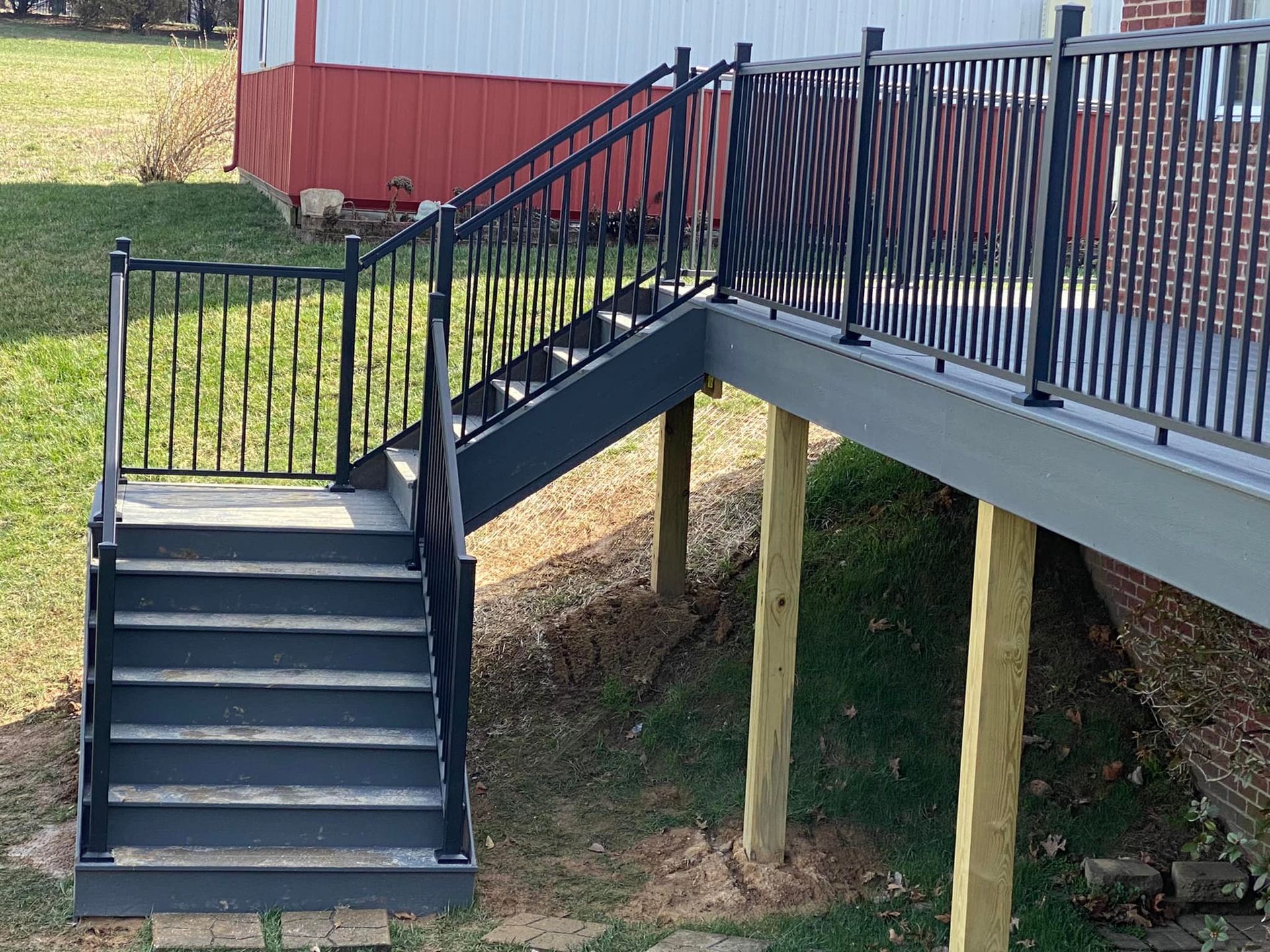 A deck with stairs leading up to it and a metal railing.