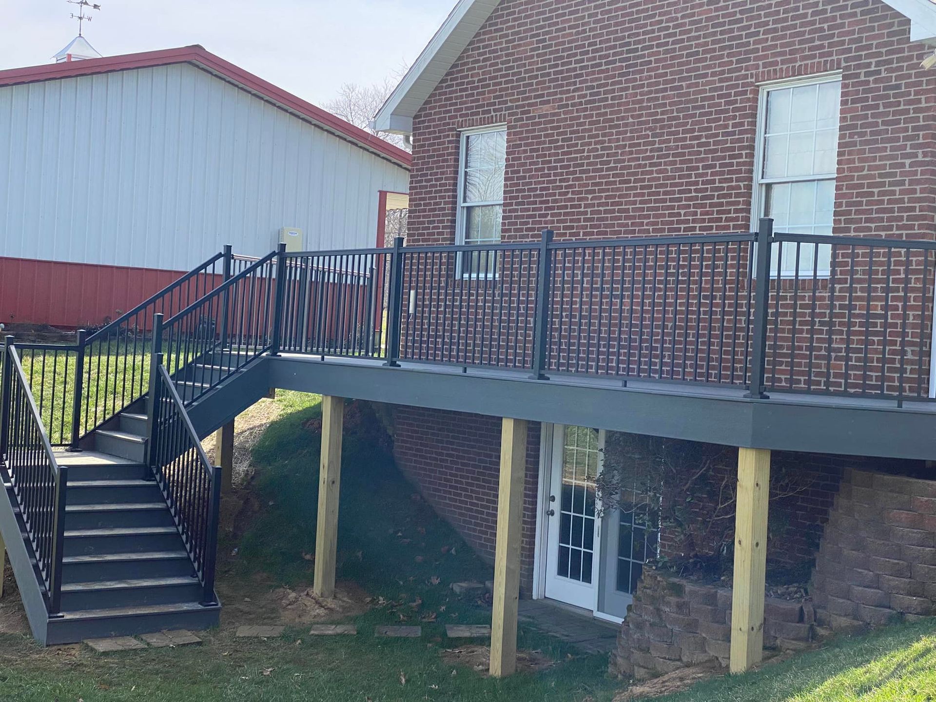 A brick house with a deck and stairs in front of it.