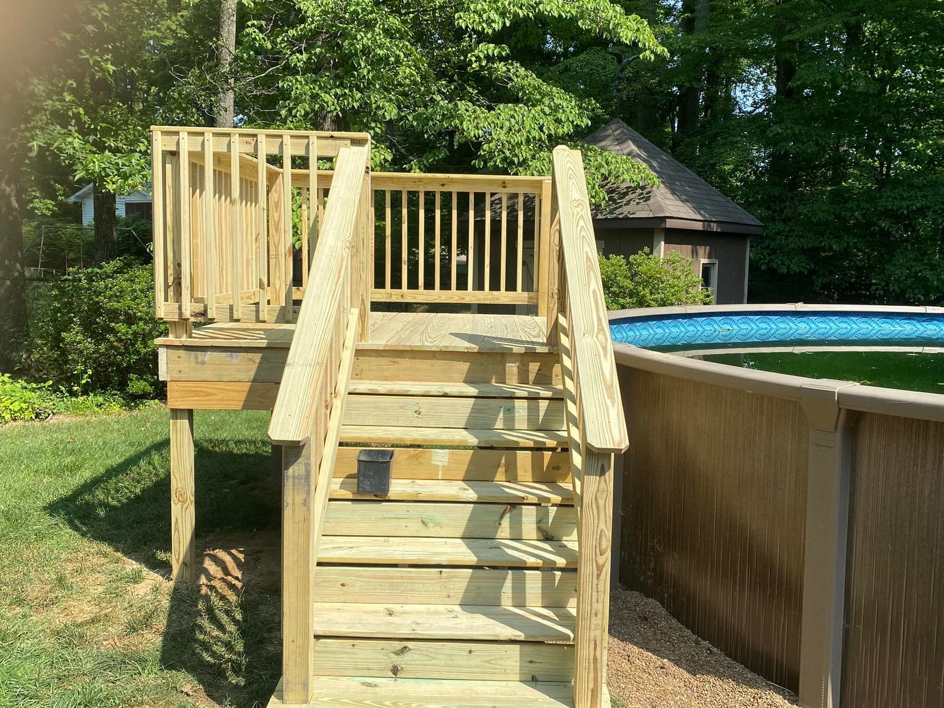 A wooden deck with stairs leading up to it next to a pool.