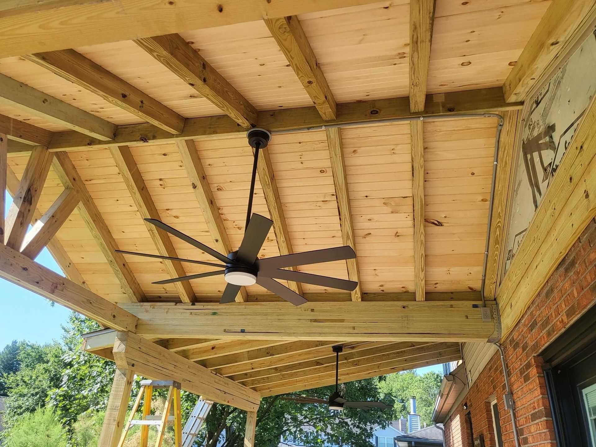 A ceiling fan is hanging from the ceiling of a wooden structure.