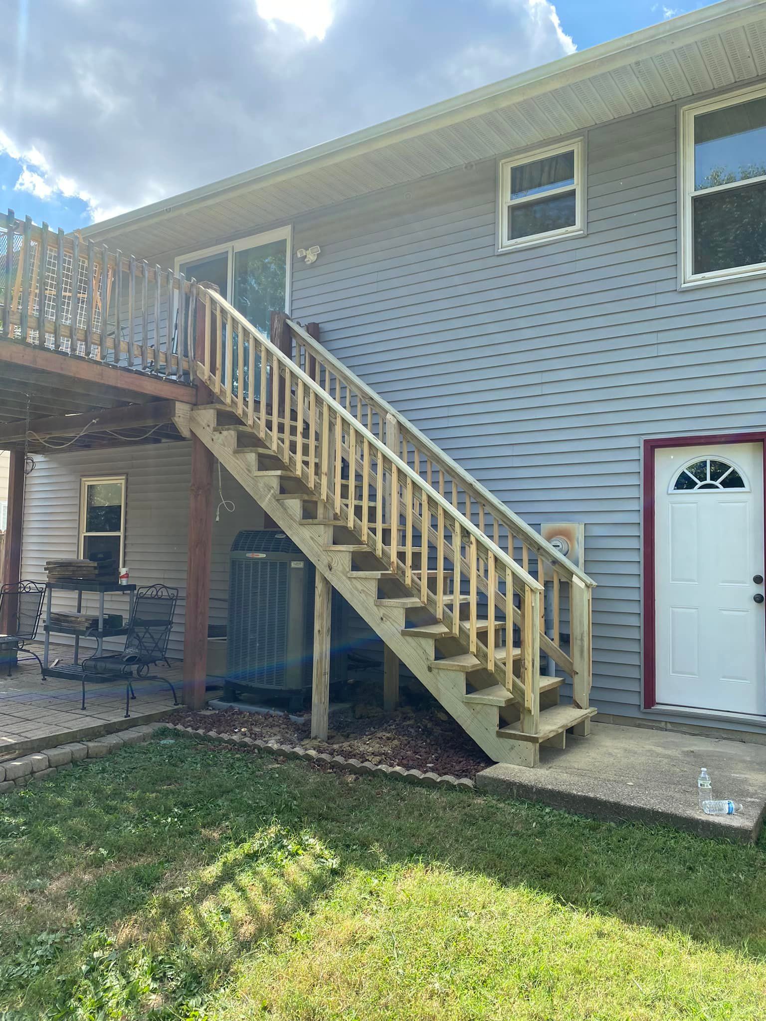 A house with stairs leading up to the second floor and a deck.