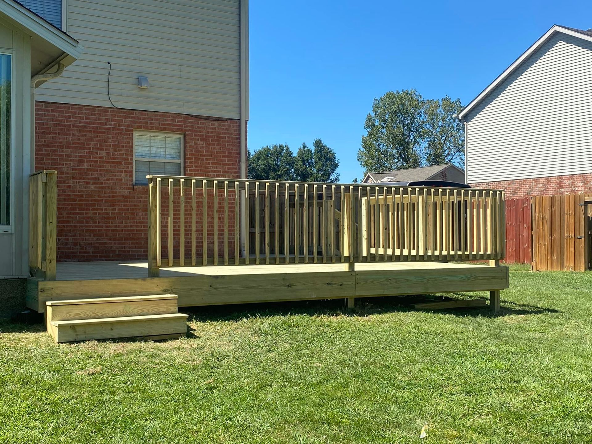 A wooden deck with stairs is in the backyard of a house.