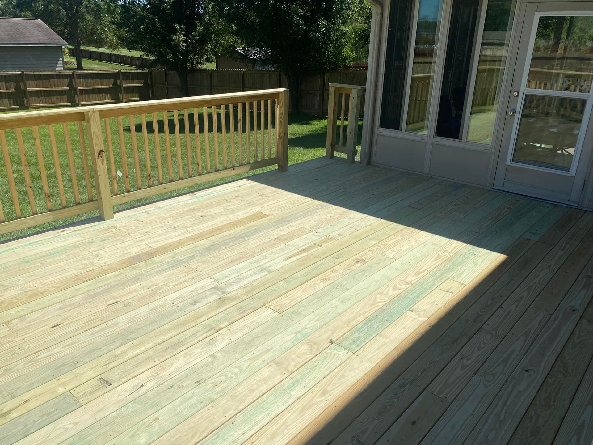 A wooden deck with a railing and a sliding glass door