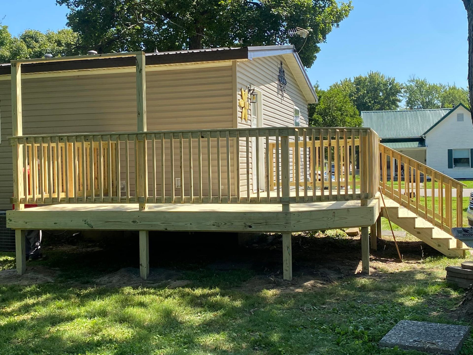 A wooden deck with stairs leading up to it is in front of a house.