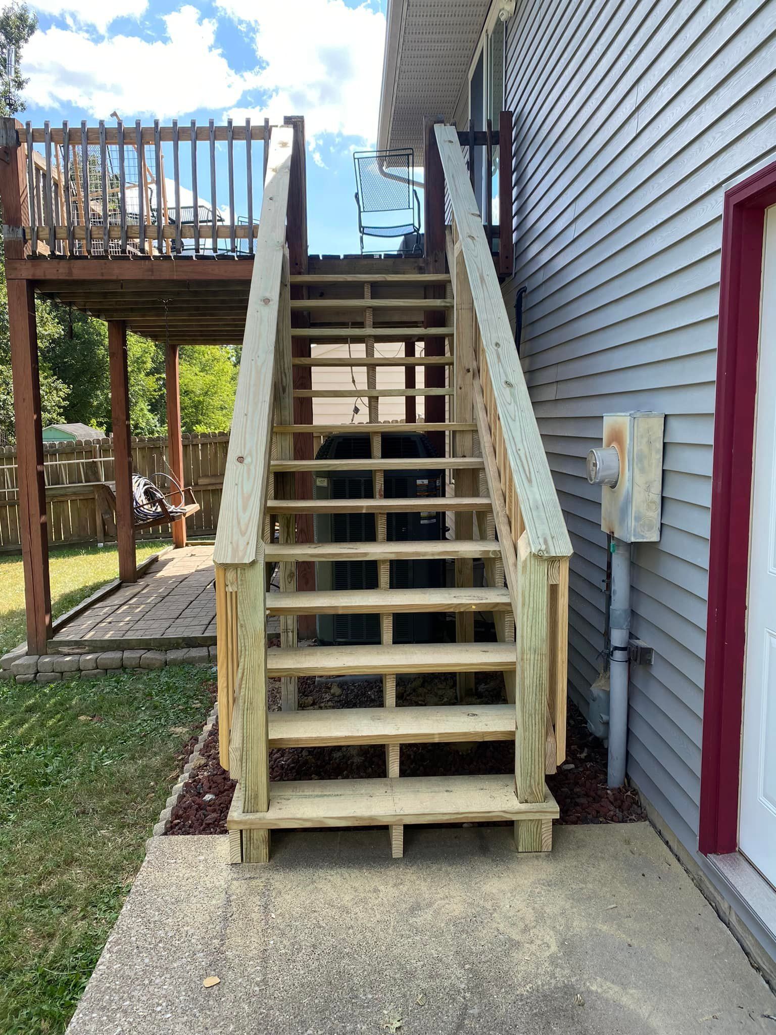 A set of wooden stairs leading up to a deck on the side of a house.