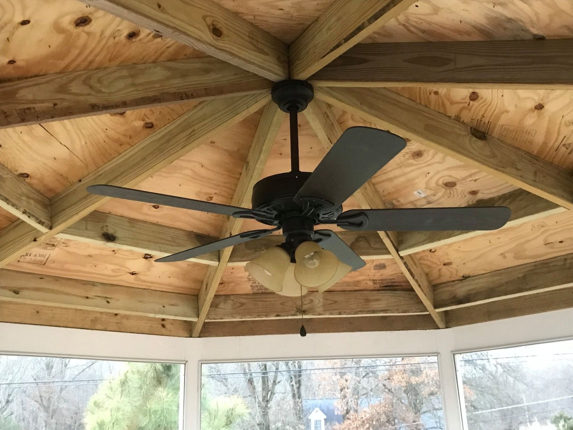 A ceiling fan is hanging from the ceiling of a gazebo.