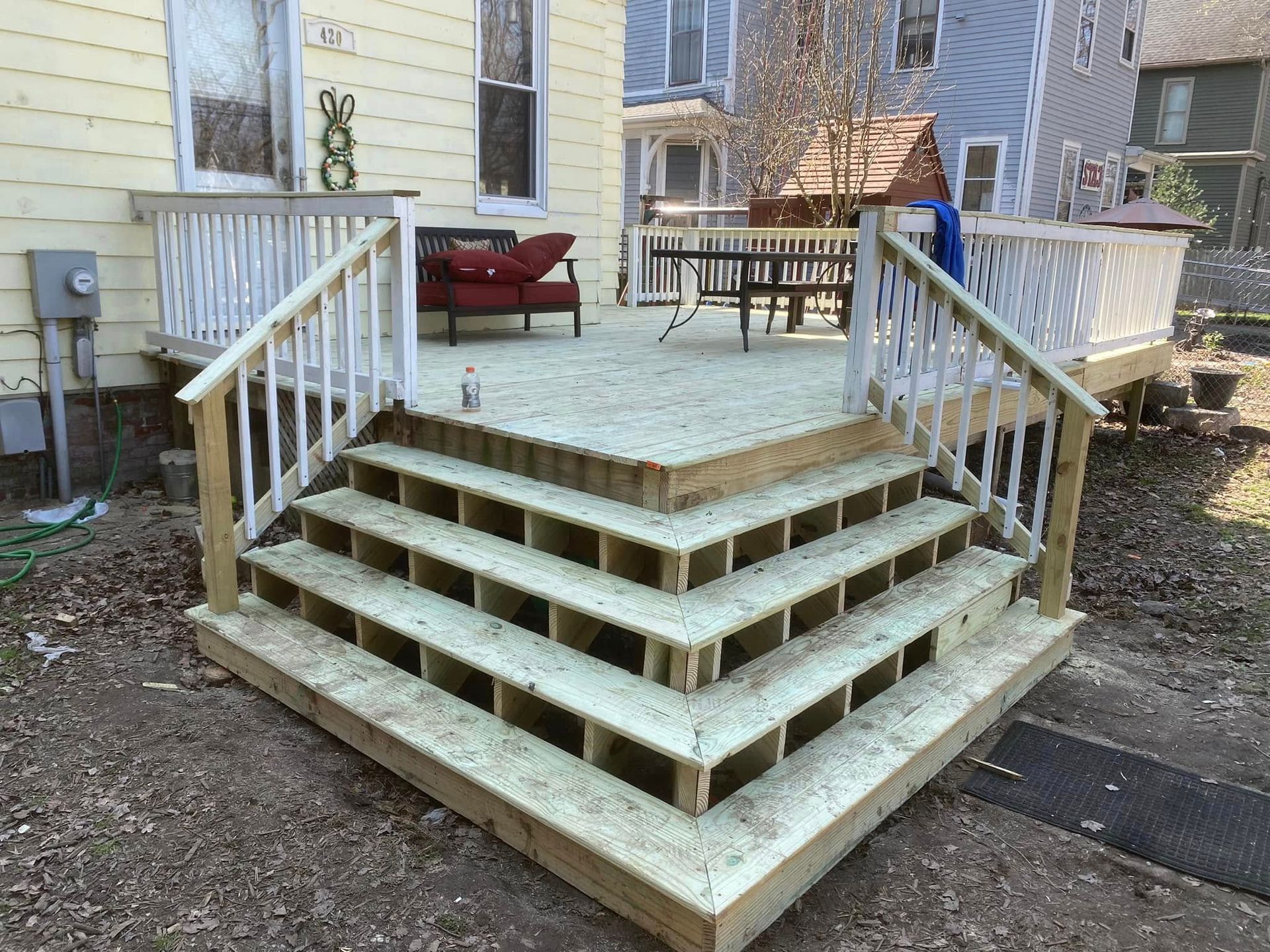 A wooden deck with stairs leading up to it is in front of a house.
