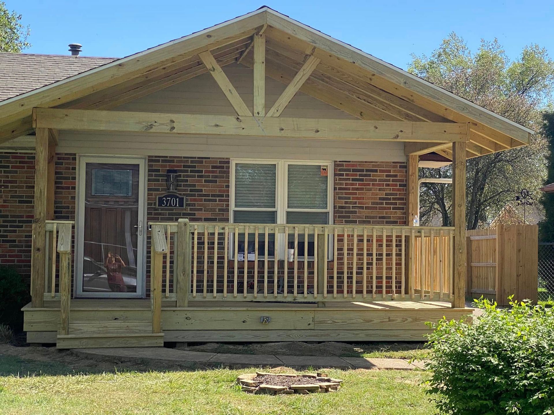 A brick house with a wooden porch and a fire pit in front of it.