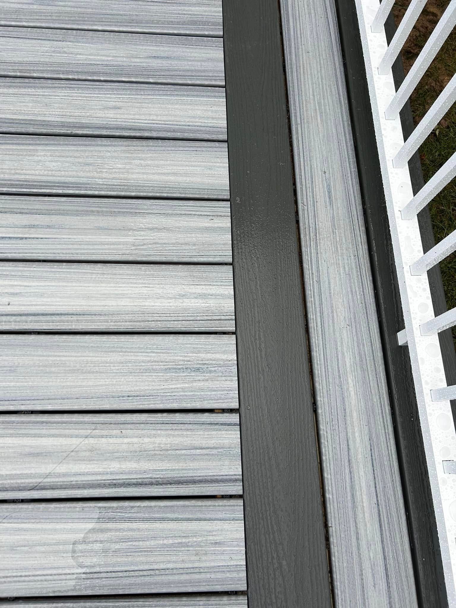A close up of a wooden deck with a black railing.