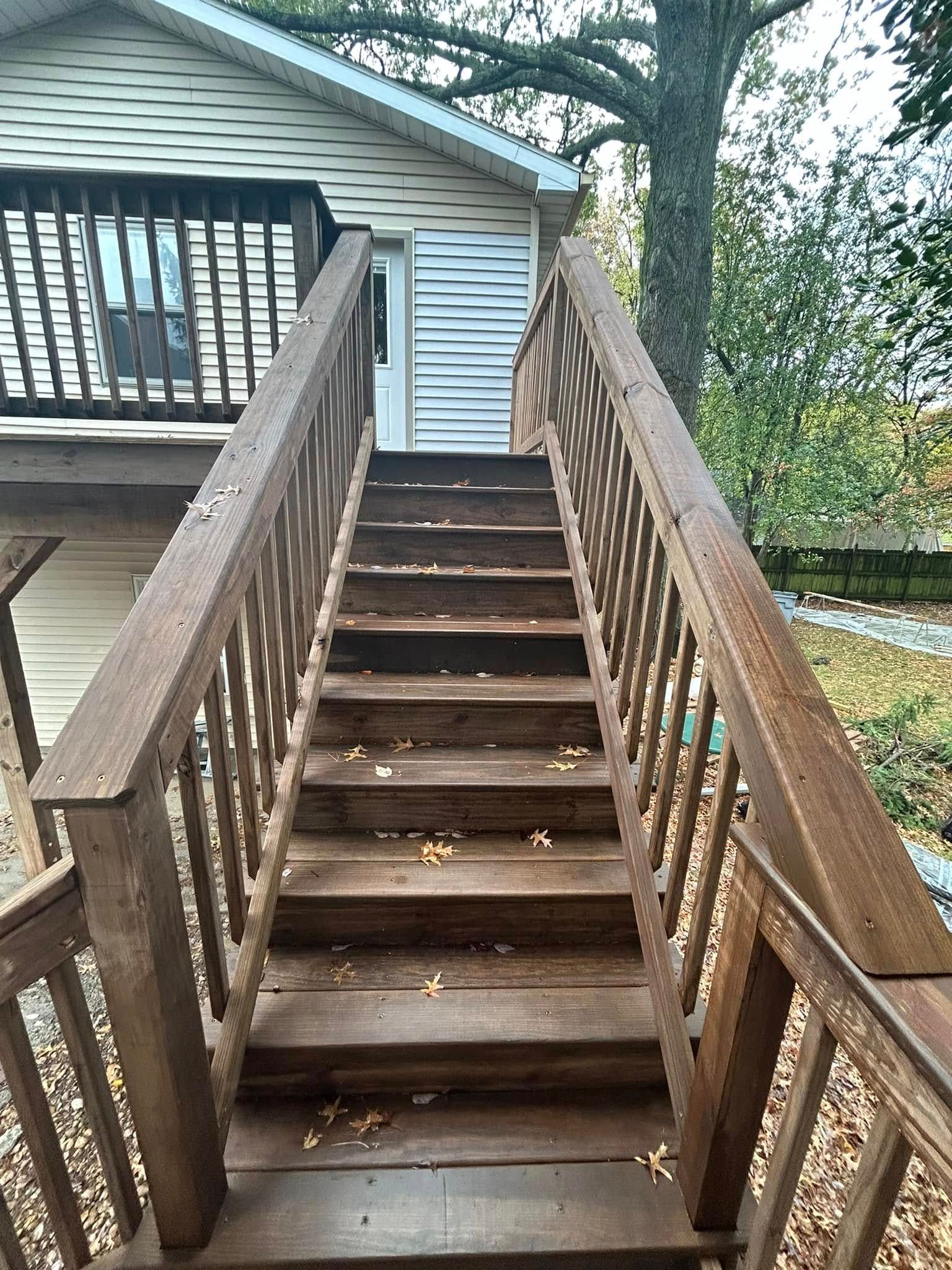 A wooden deck with stairs leading up to a house.