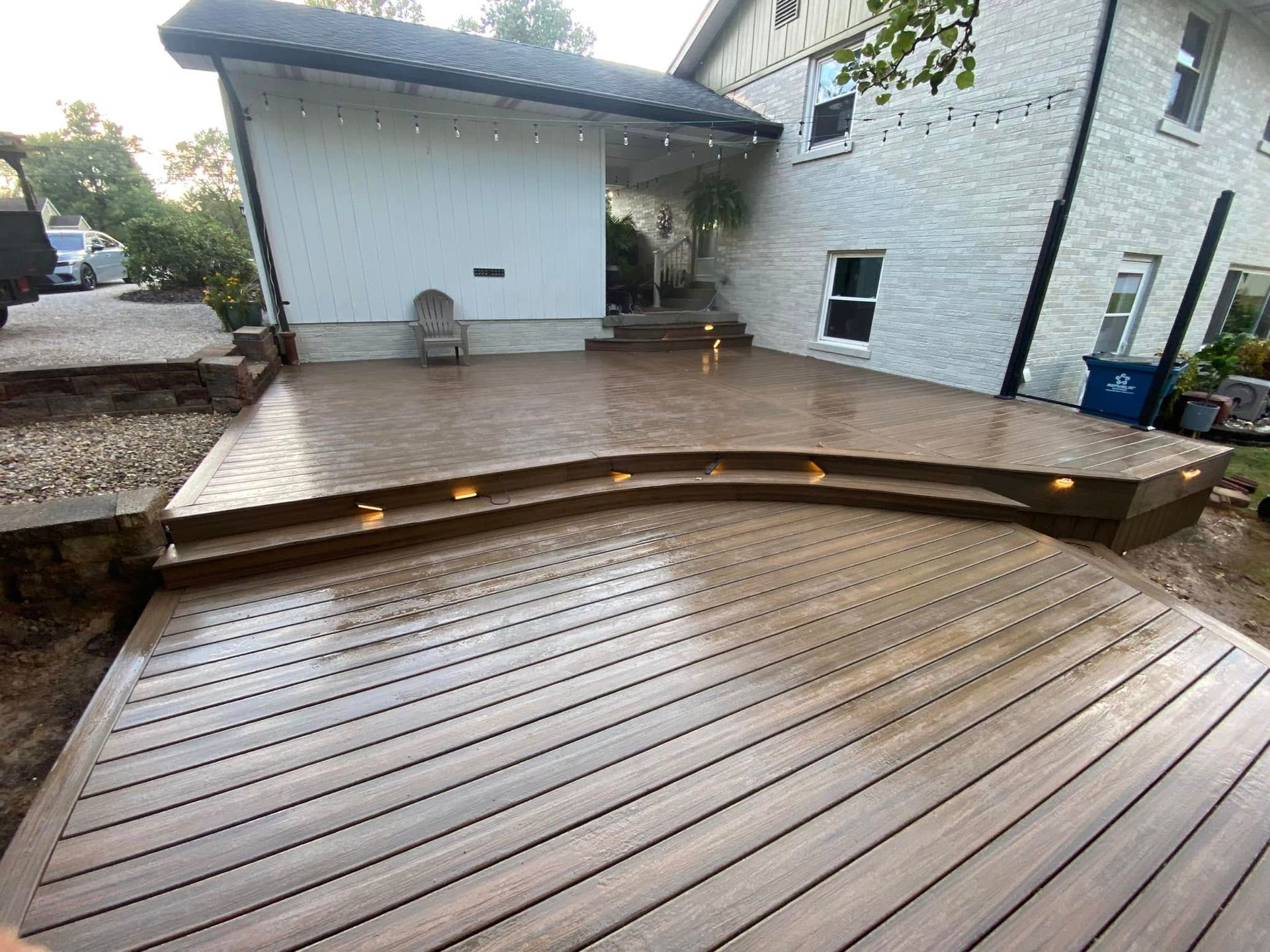 A wooden deck is sitting in front of a white house.