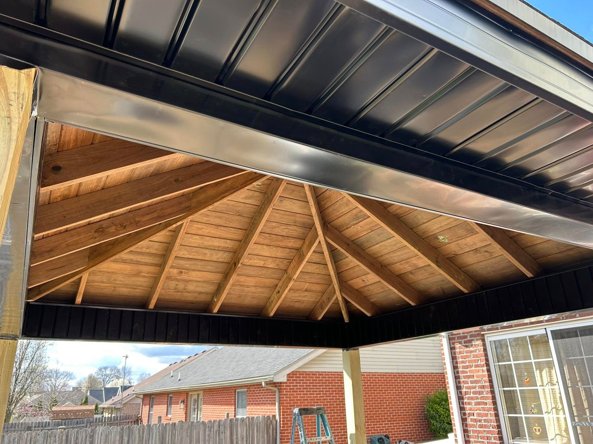 The ceiling of a gazebo is made of wood and metal.