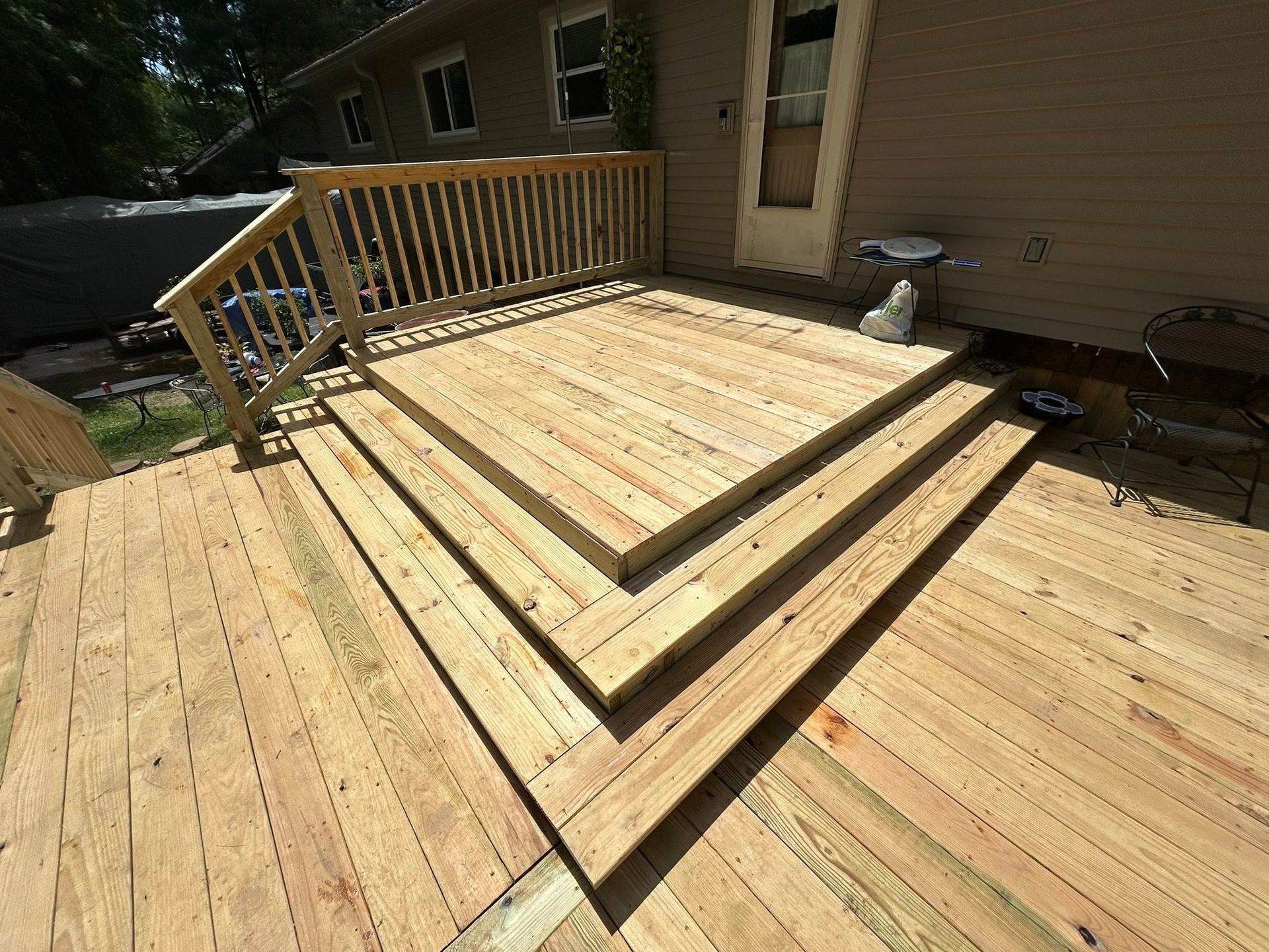 A wooden deck with stairs and a railing in front of a house.
