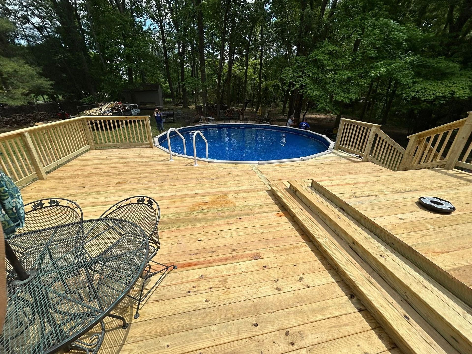 A wooden deck with a swimming pool in the background.
