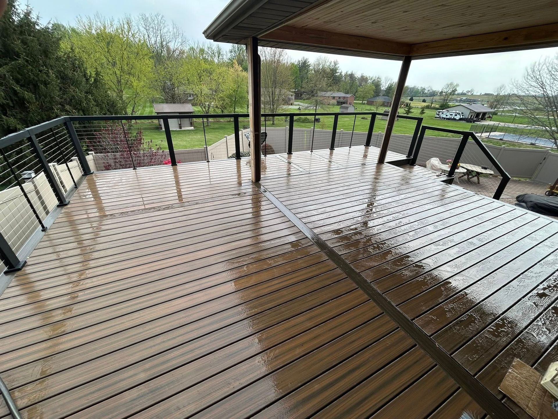 A wooden deck with a metal railing and a view of a park.