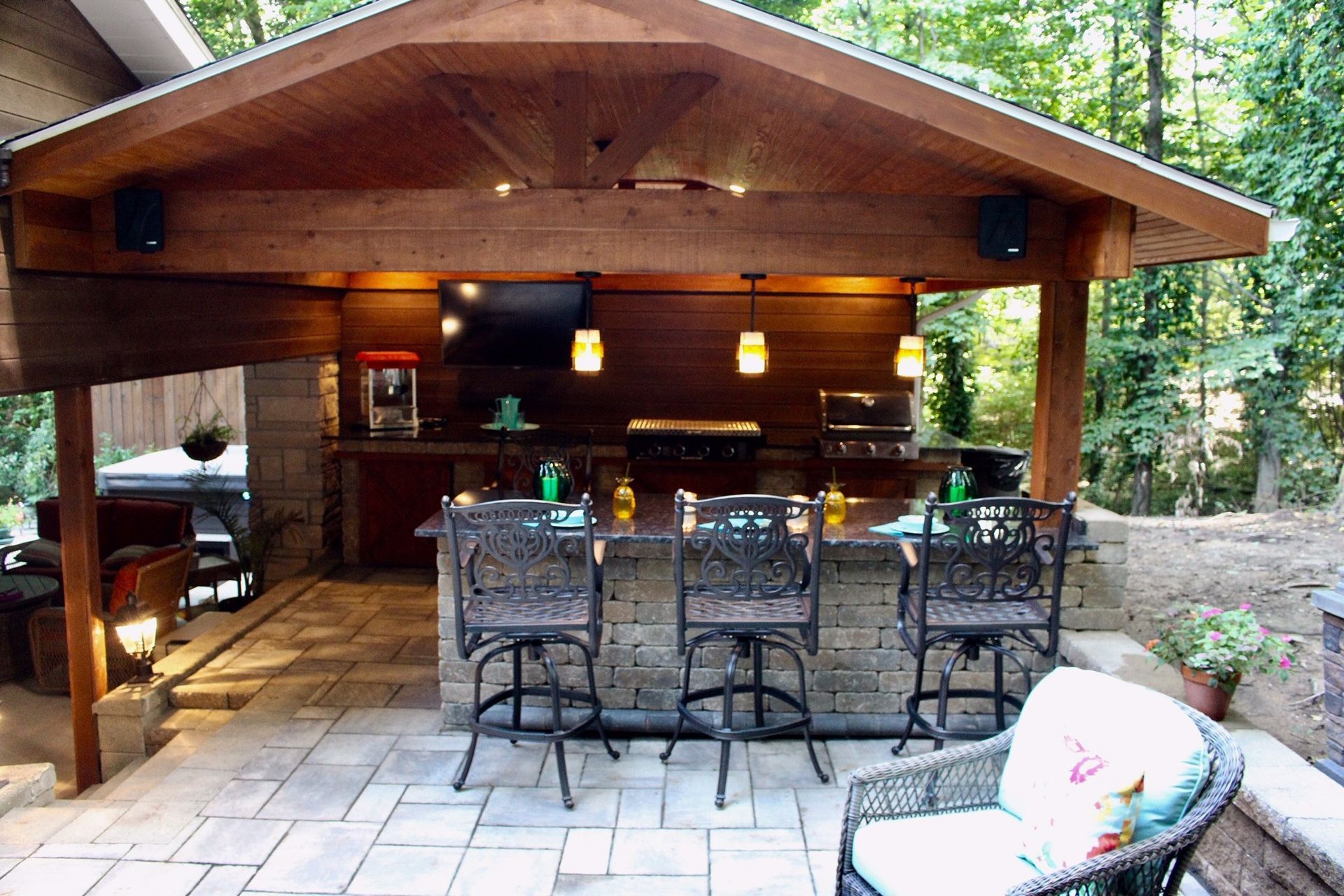 A covered patio with a table and chairs under a wooden roof