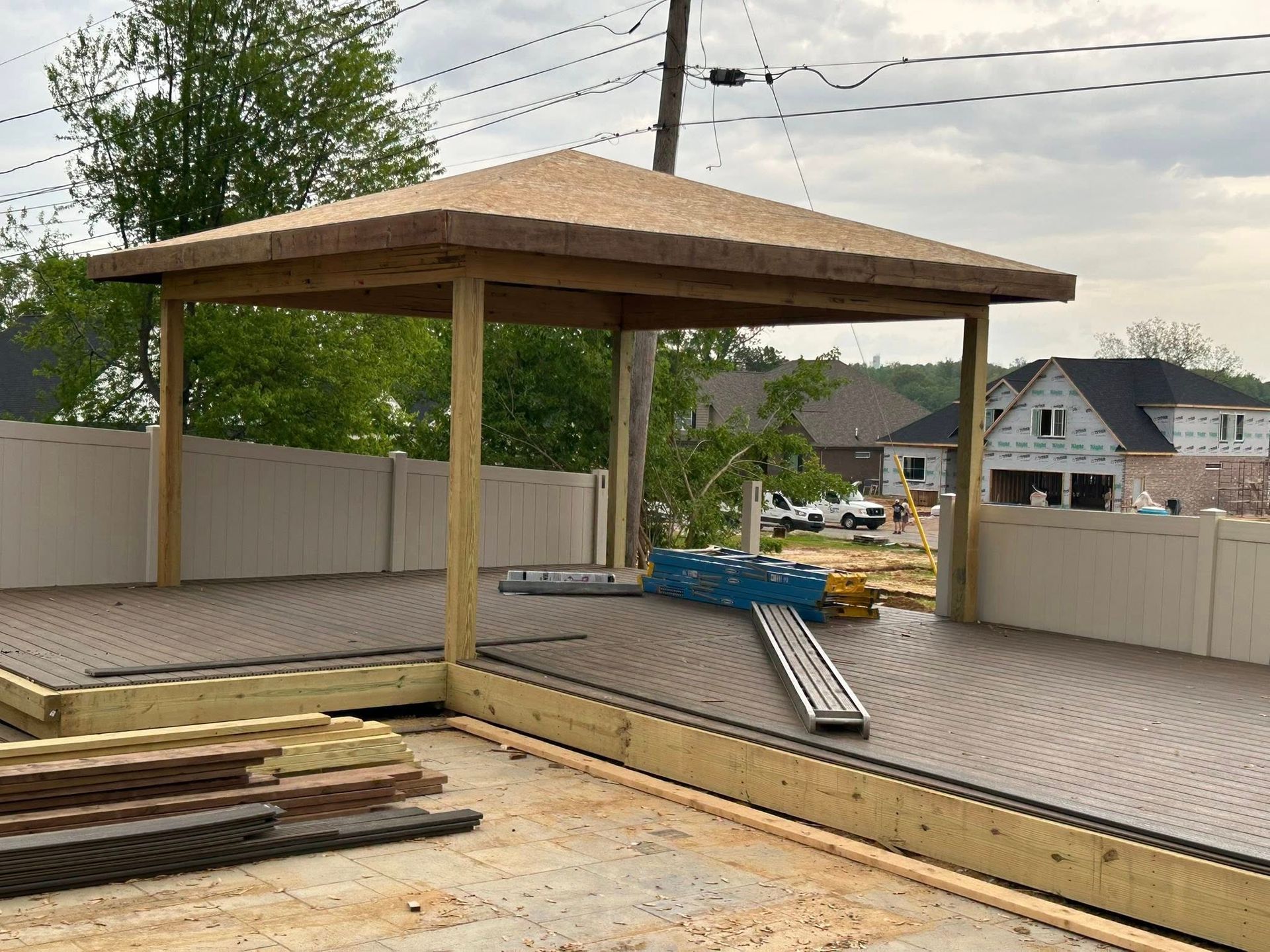 A wooden gazebo is being built in the backyard of a house.