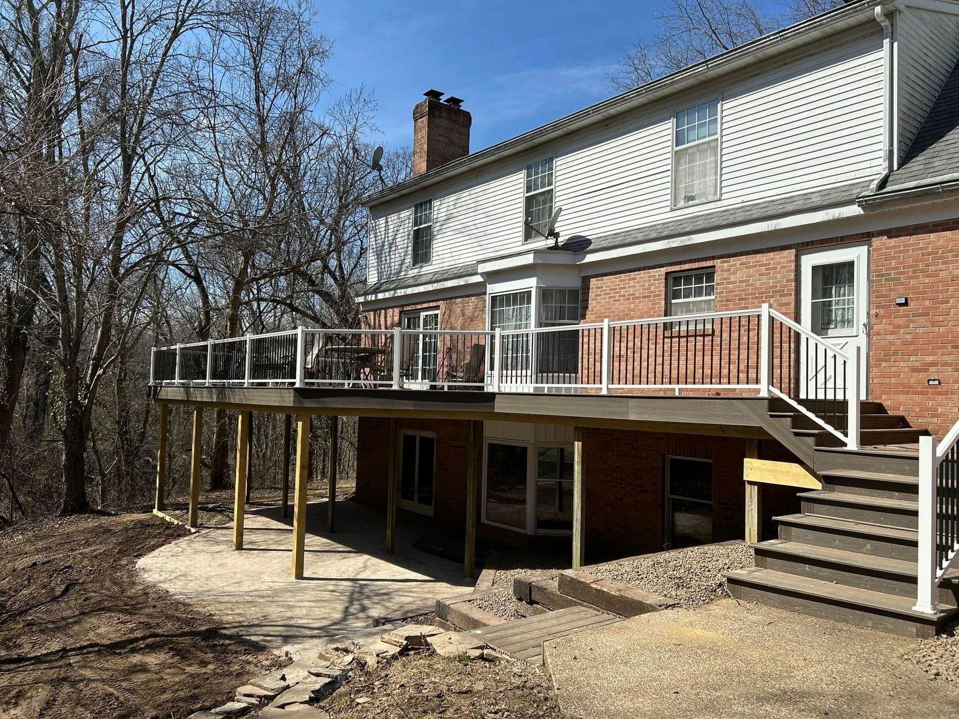 A large brick house with a large deck and stairs.