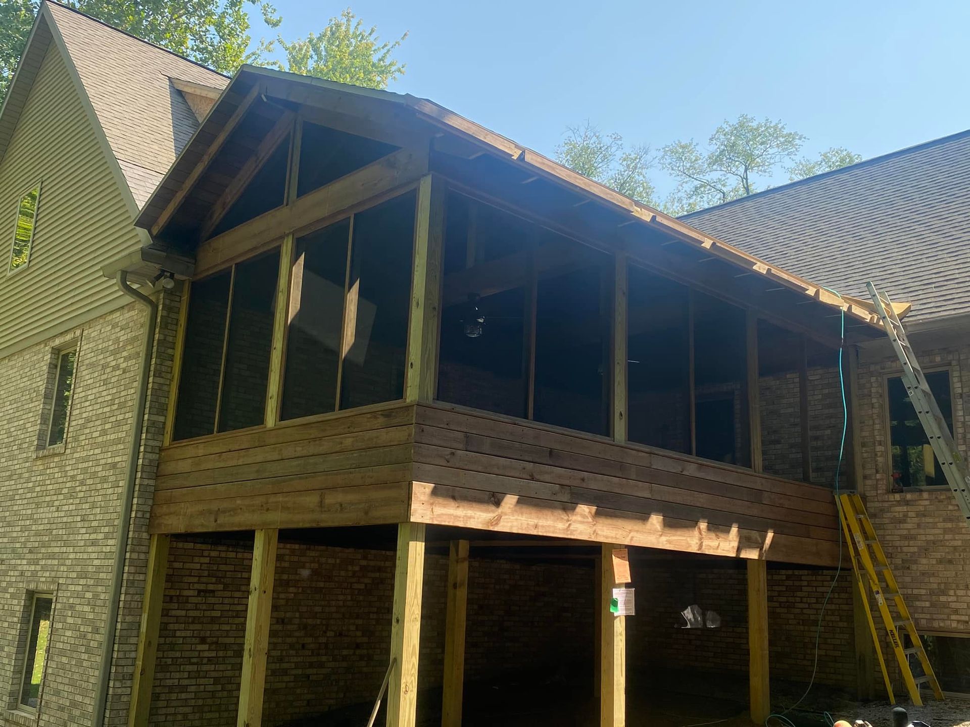 A screened in porch is being built on the side of a house.
