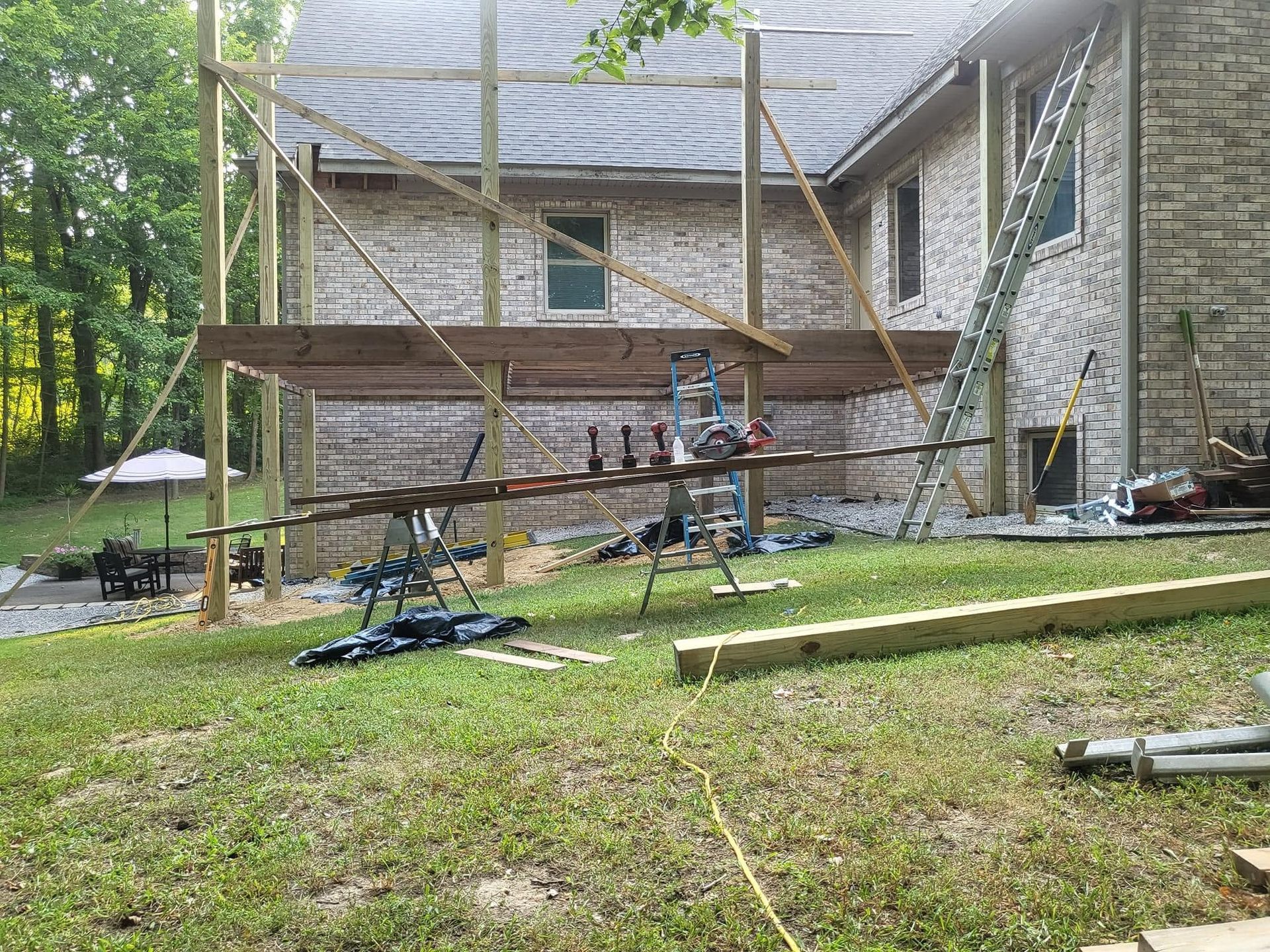 A wooden deck is being built in front of a brick house.