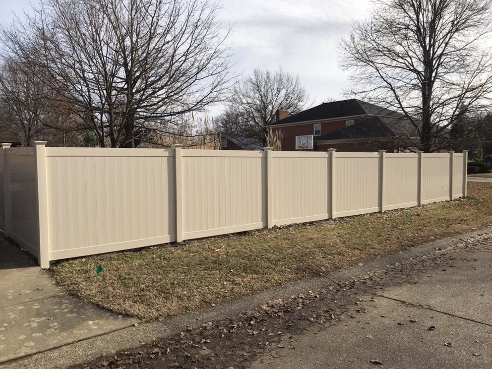 A white vinyl fence is sitting next to a sidewalk in front of a house.