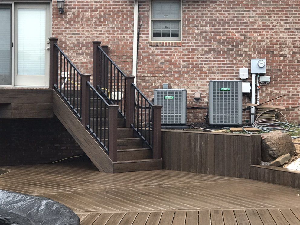 A wooden deck with stairs leading up to a brick house