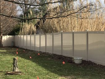 A white fence surrounds a yard with a statue in the middle of it.