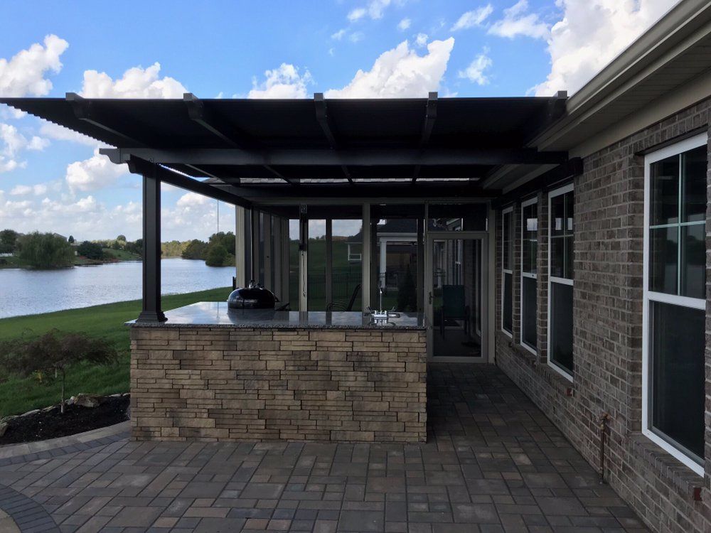 A brick house with a patio area and a large window overlooking a lake.