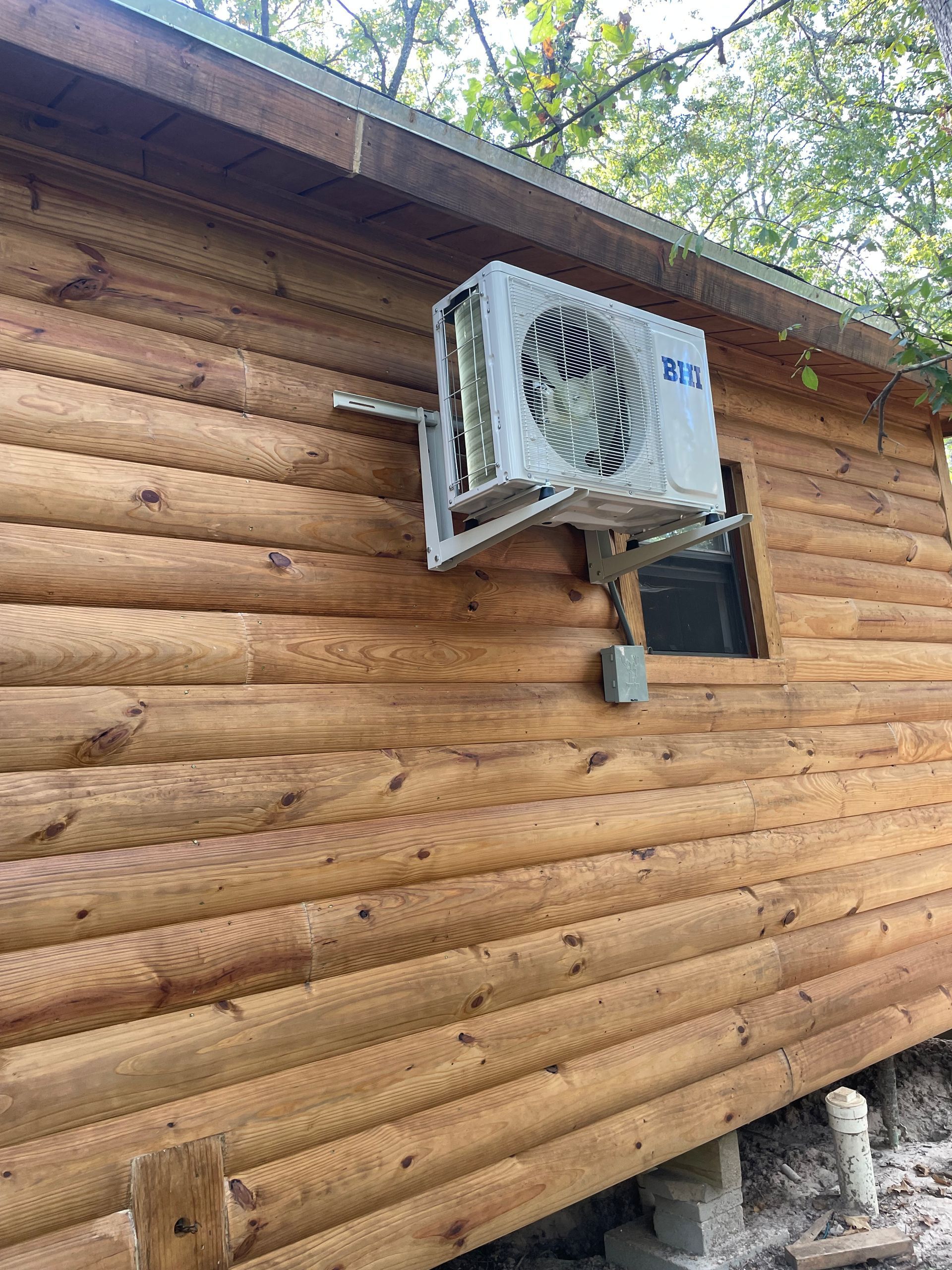 Air conditioner unit mounted on a wooden cabin wall.