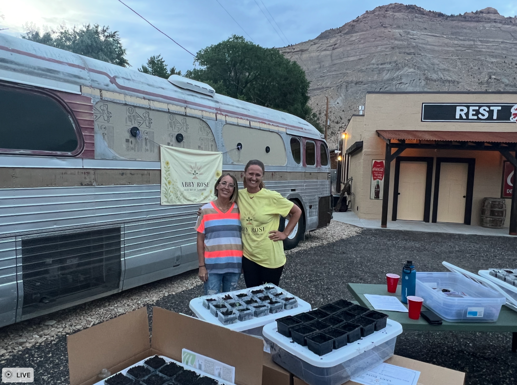 Two women pose near a vintage bus and building with 