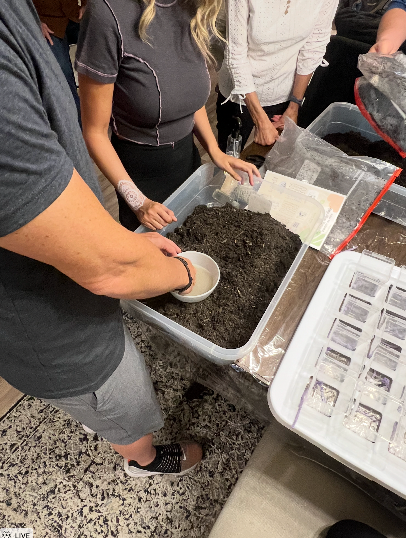 People preparing soil in a container, possibly for gardening or planting.