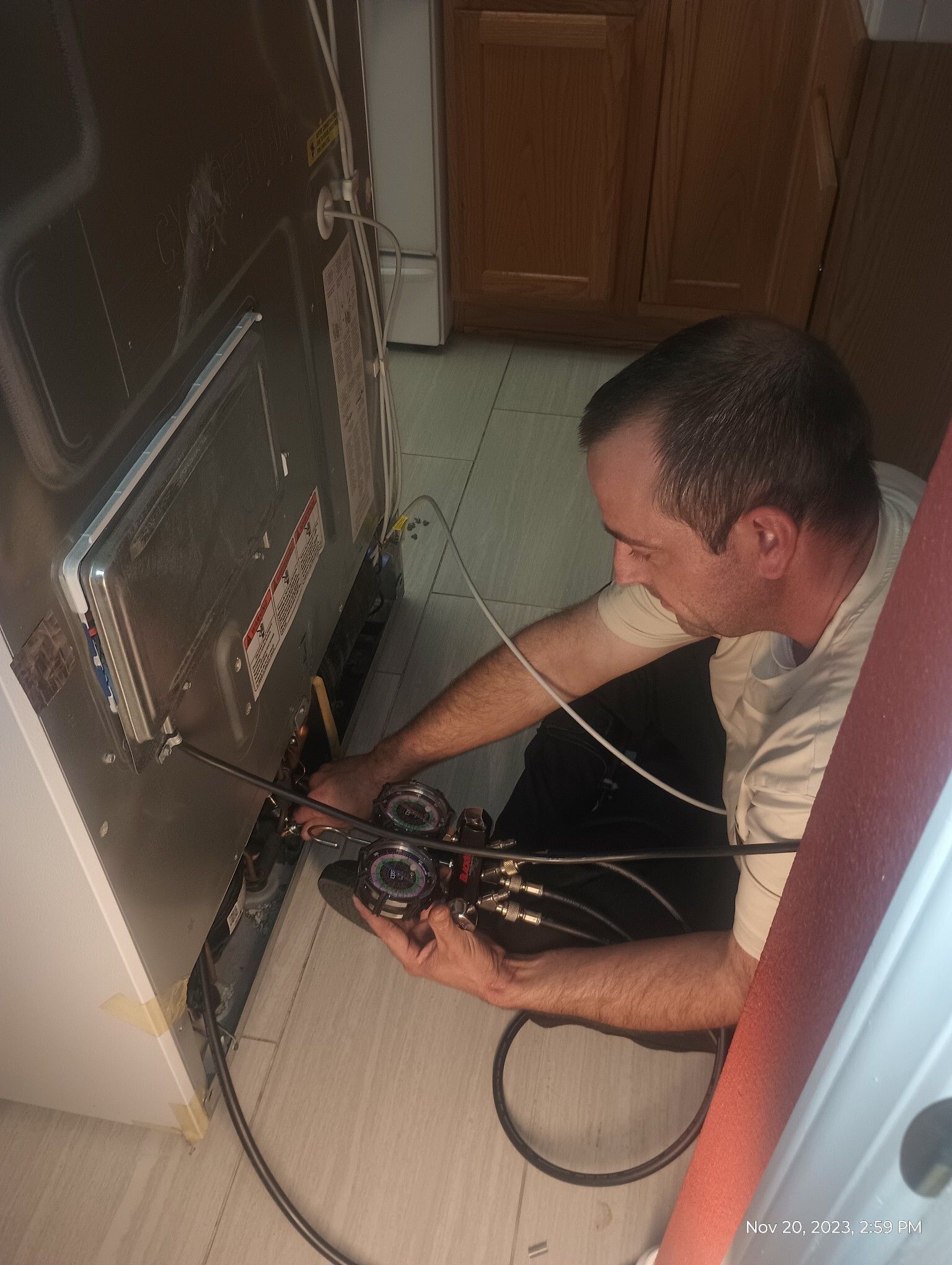Technician inspecting wiring inside a wall opening near a door.