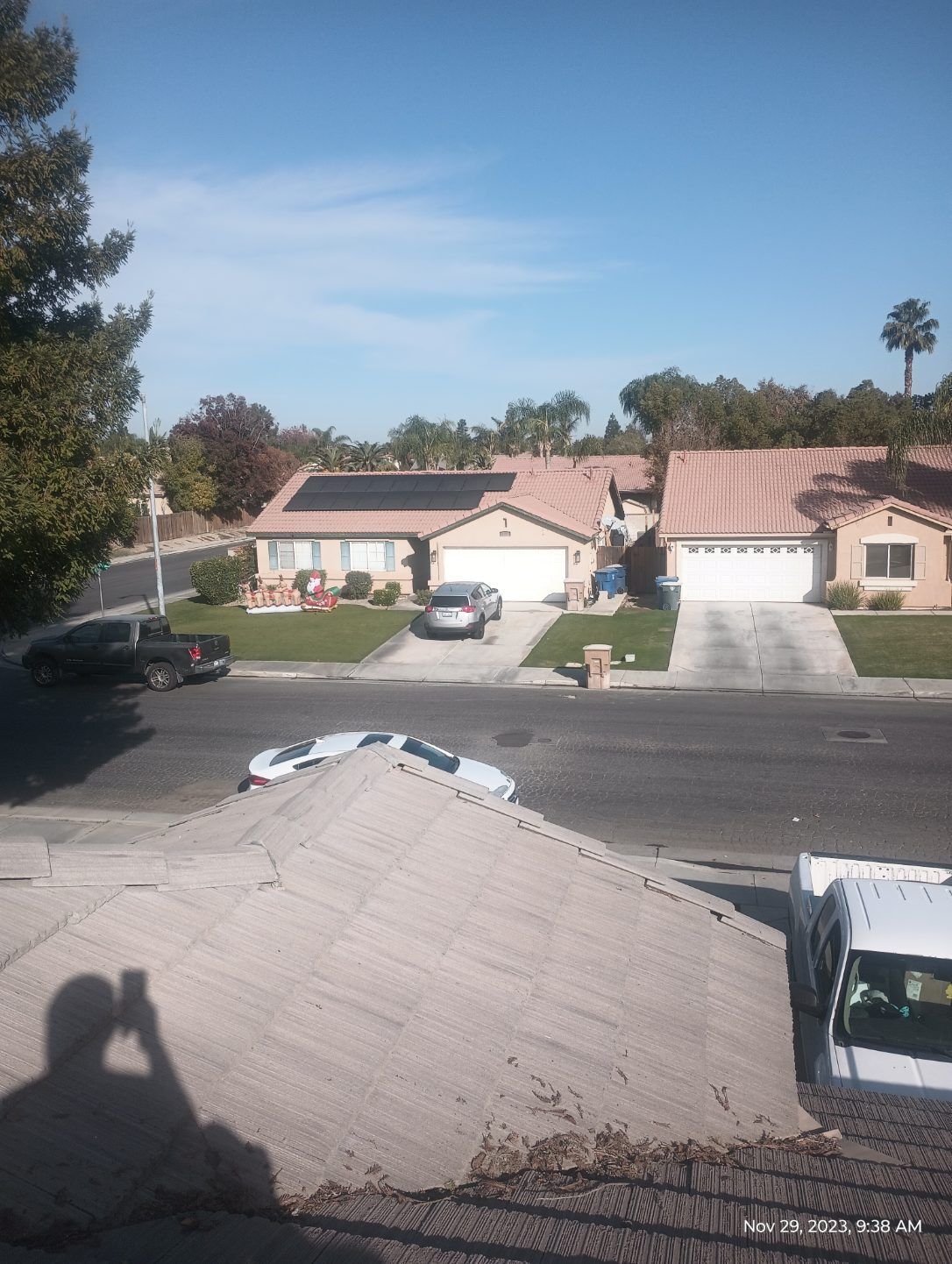 Suburban street with parked cars and single-story houses under a clear blue sky