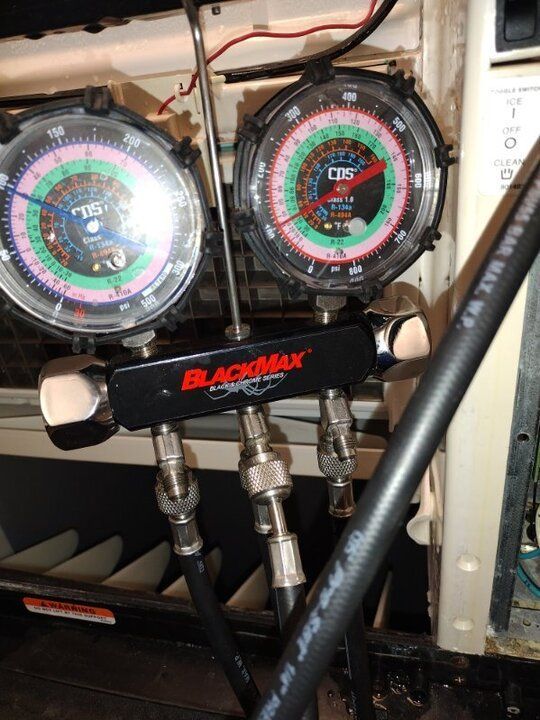 Blackmax HVAC manifold gauges with hoses attached in a mechanical or service compartment