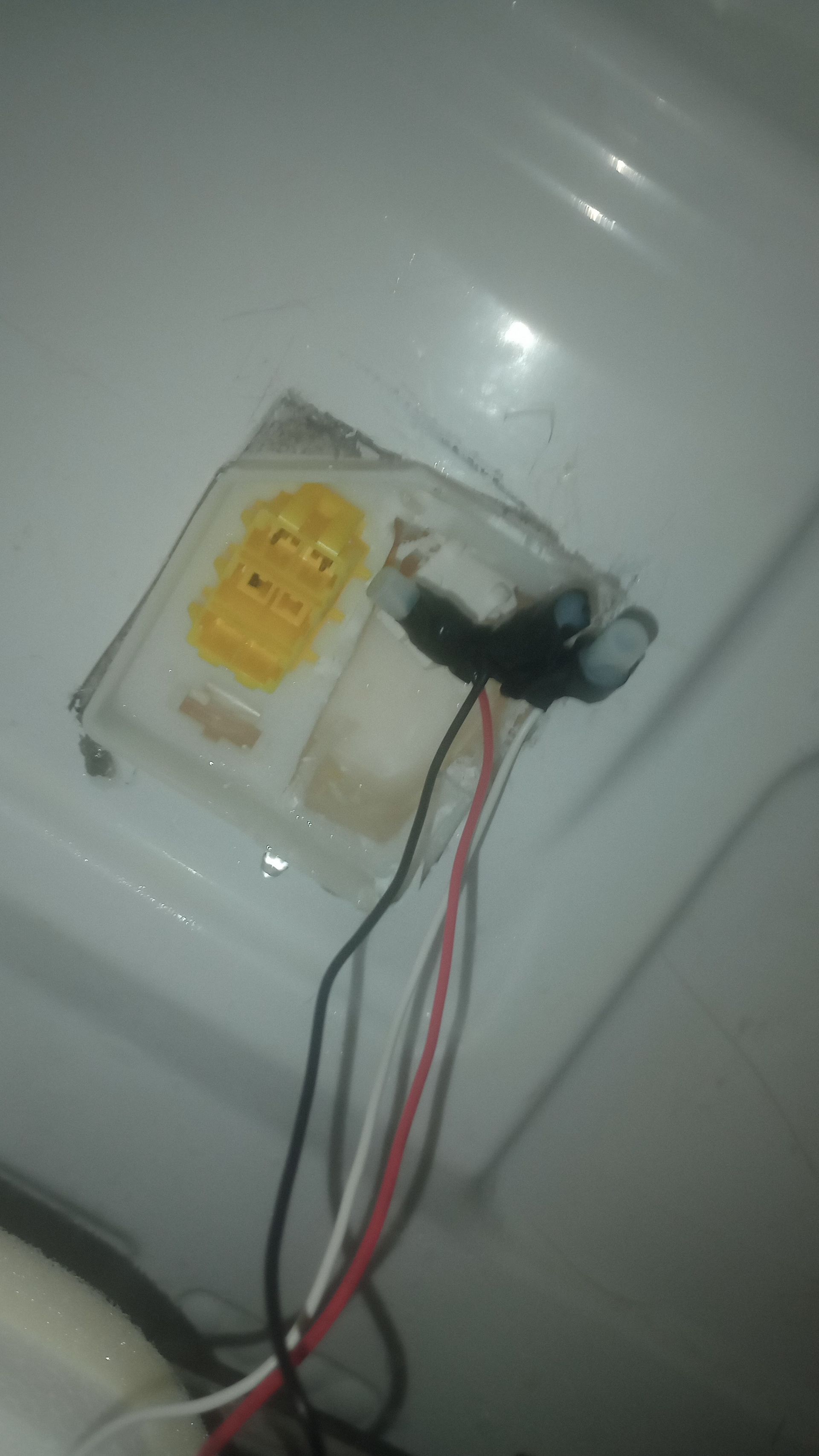 A wall outlet with exposed wires and a yellow electrical component taped on top.
