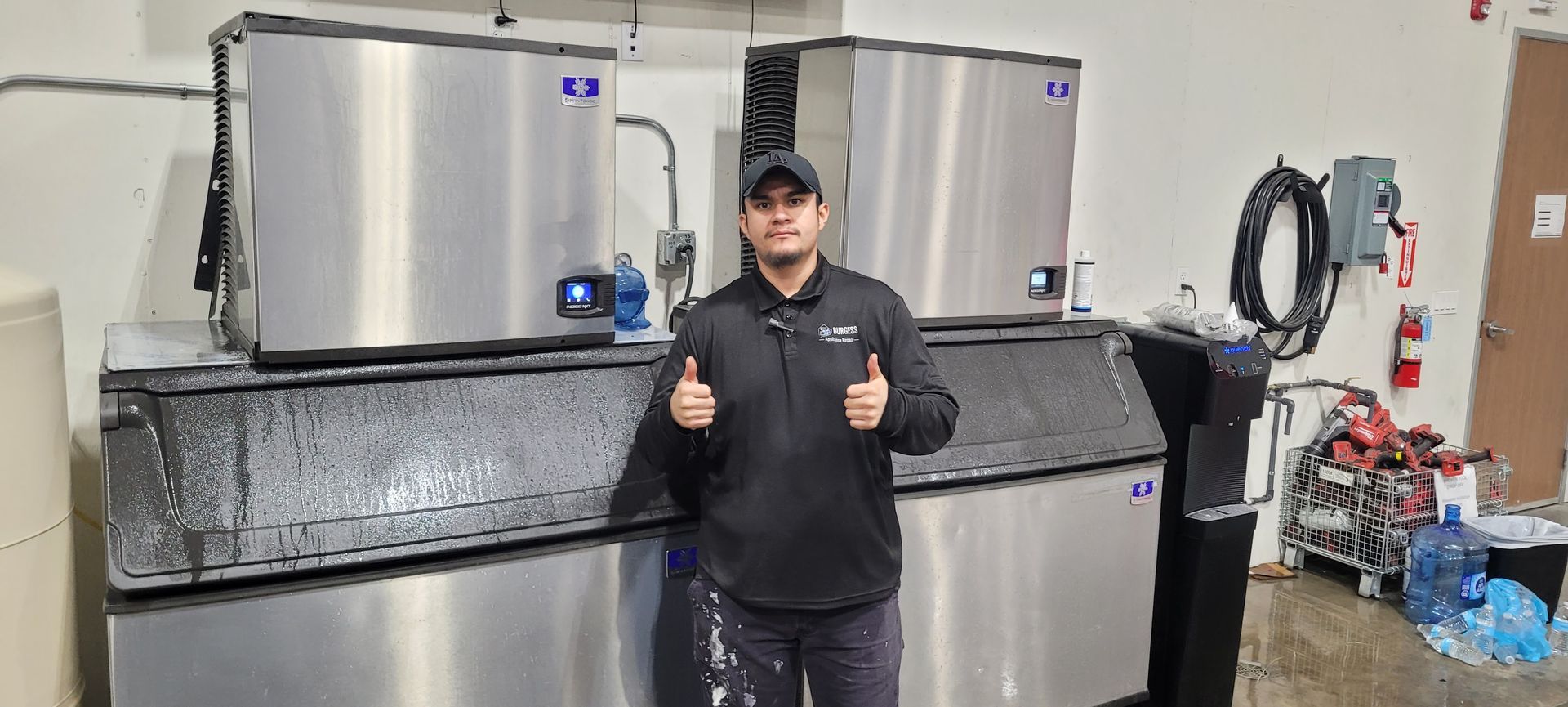 Person giving thumbs up in a workshop beside large stainless steel machines
