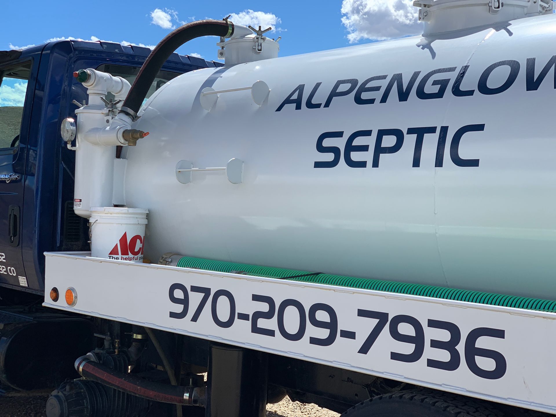 White Alpenglow Septic service truck with blue lettering and phone number 970-209-7936