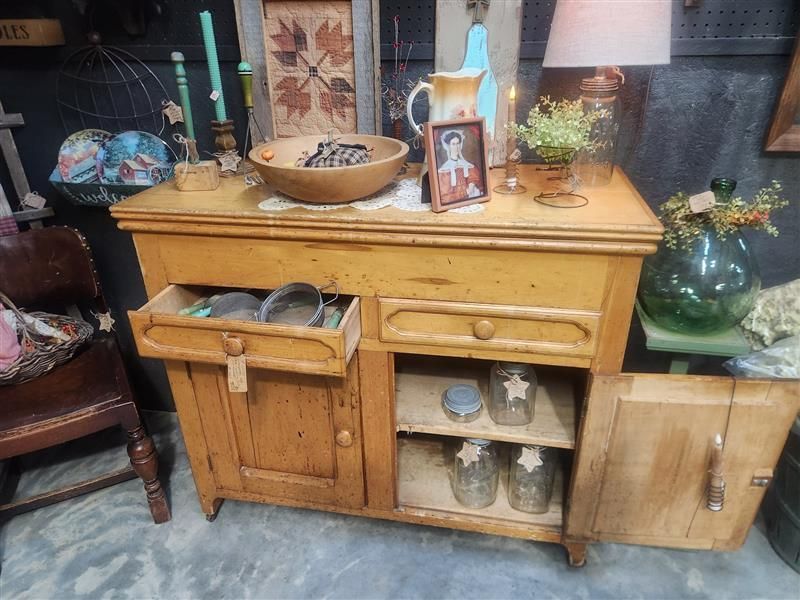 Antique wooden cabinet with open drawer and door, holding jars and bowls.