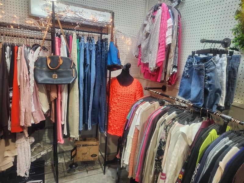 Clothes racks with a variety of garments in a store setting, with a mannequin in an orange dress.