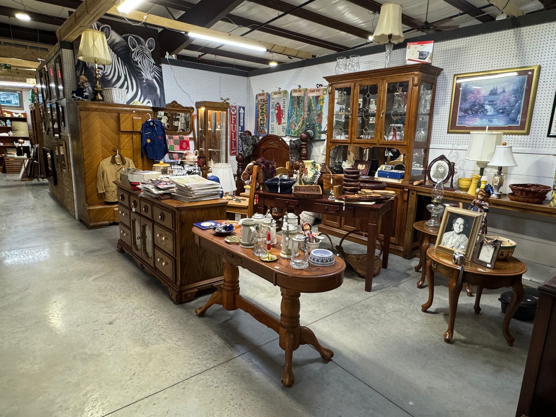 Interior view of an antique shop filled with furniture, decor, and art; neutral lighting.