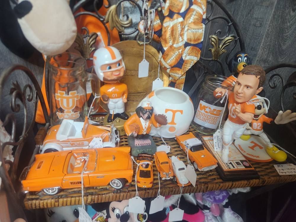 Shelves with University of Tennessee merchandise in orange and white. Includes bobbleheads, cars, and other collectibles.