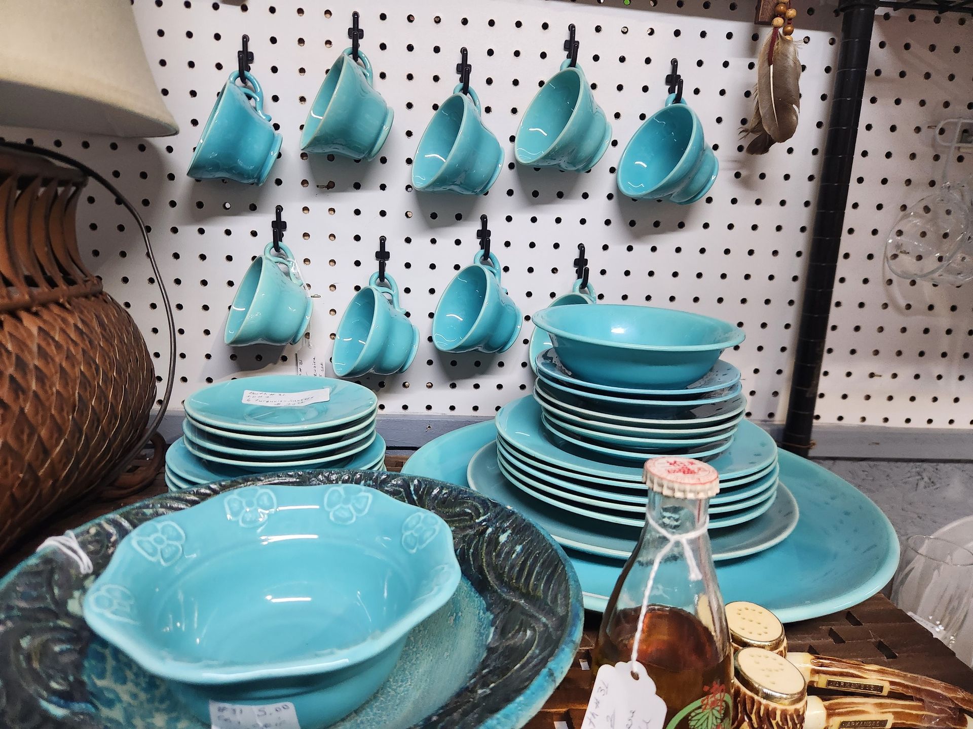Turquoise dishware set displayed on a wall and table.
