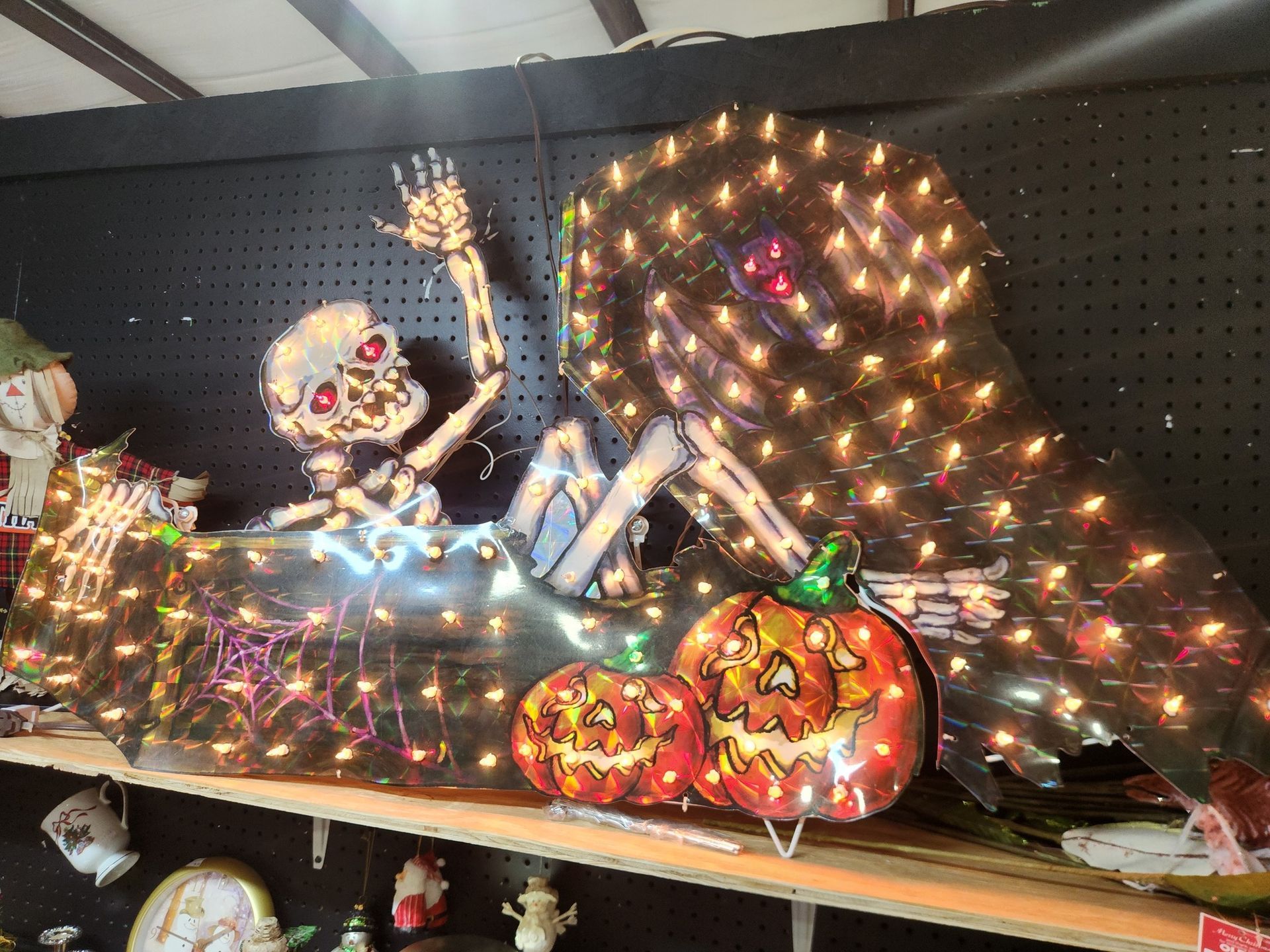 Halloween skeleton in a bathtub decorated with lights, next to two jack-o'-lanterns.