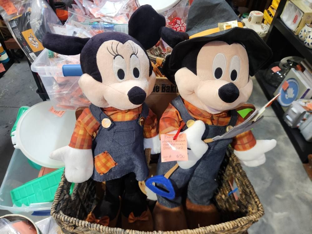 Minnie and Mickey Mouse plush toys in overalls and straw hats, in a basket.
