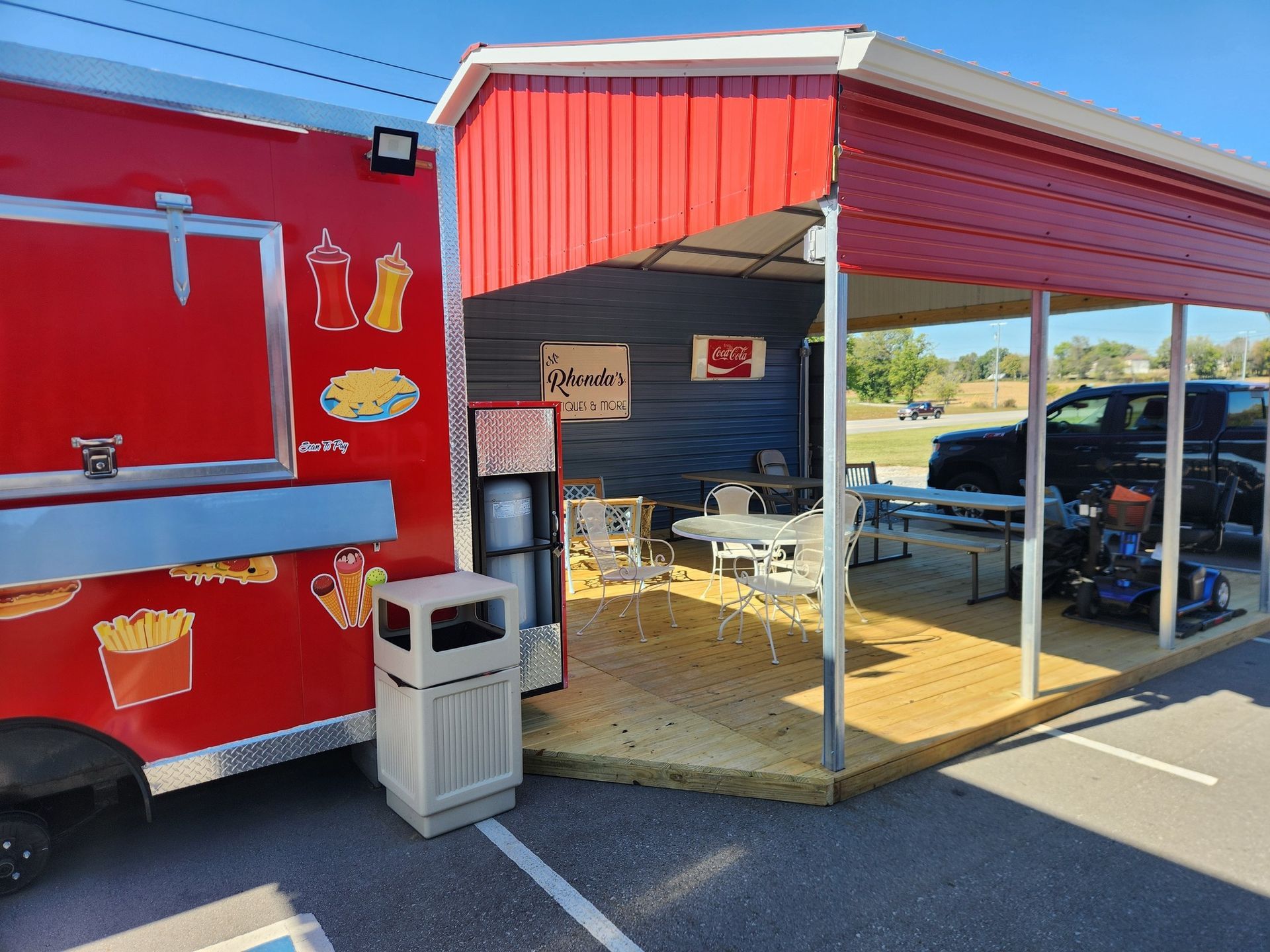 Red food truck with attached red awning and seating area.