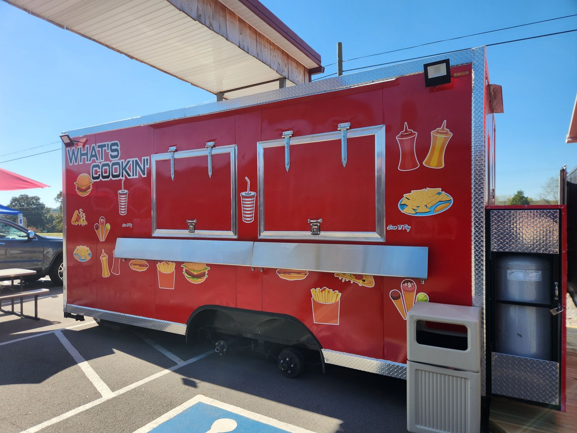 Red food truck with service windows; side view with food icons.