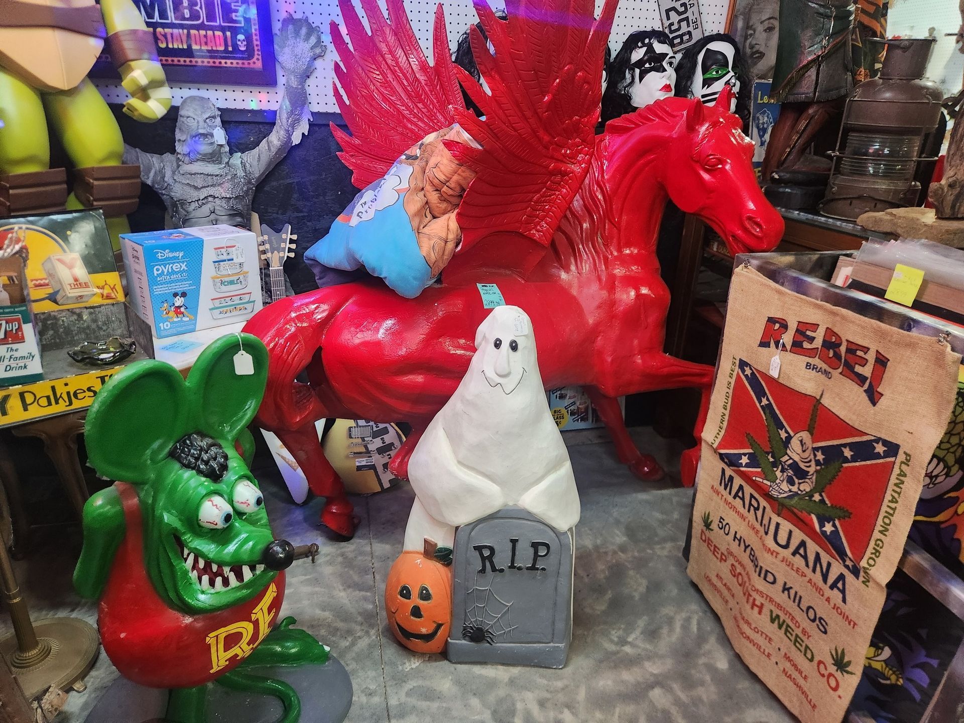 A quirky display with a red winged horse, a ghost statue, and a "Rebel" marijuana bag.