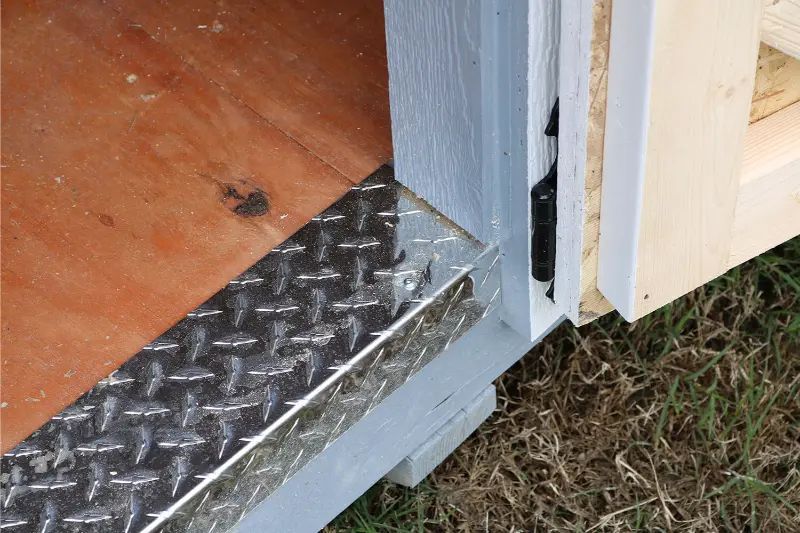Diamond plate threshold at a shed doorway, transitioning to a wooden interior.