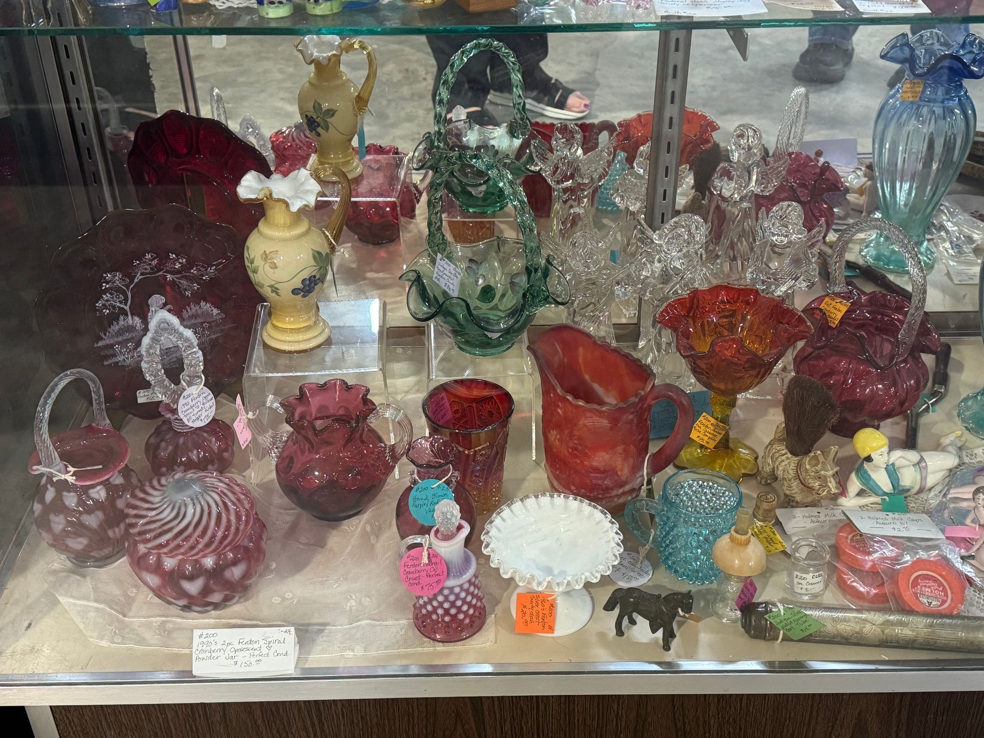 Glass display case filled with colorful vases and decorative items, some with heart and floral designs.