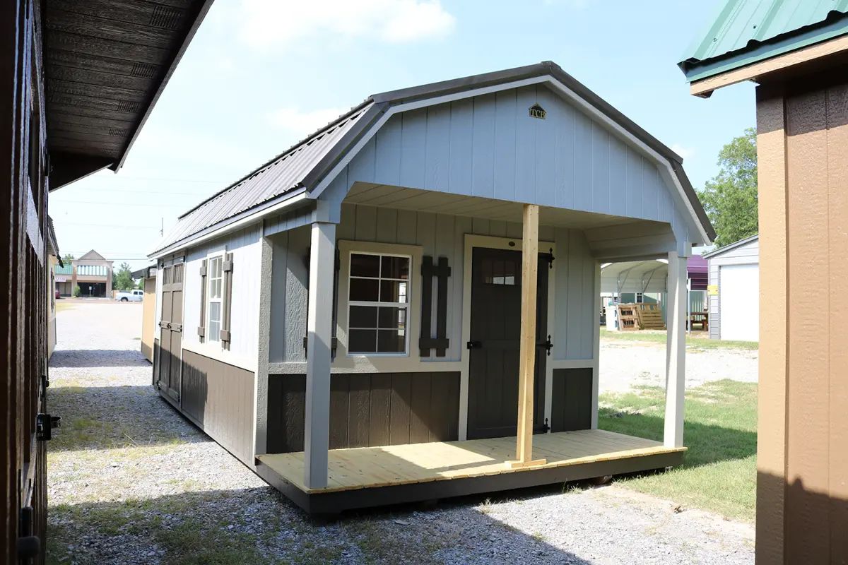 A small blue and brown barn-style shed with a porch and dark door.